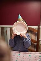 Birthday girl covering face with plate