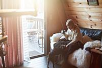 Woman drinking and petting dog on sofa at home