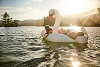 Girls playing on inflatable swan in lake