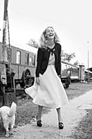 Laughing woman wearing jacket and skirt standing a