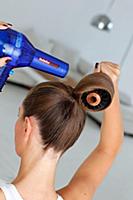 Rear view of woman holding round hair brush and bl