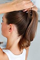 Rear view of woman tying ponytail