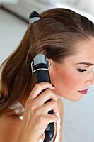 Side view of beautiful woman curling her hair with