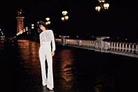 Woman in white outfit standing on bridge at night