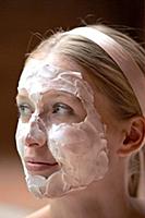 Blonde woman wearing hair band and curd mask, look