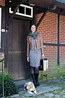 Brunette woman wearing scarf standing with suitcas