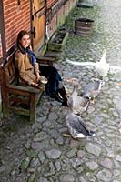 Brunette woman sitting on bench and feeding Pomera