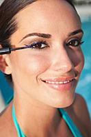 A young woman applying eyeliner to her eyelid