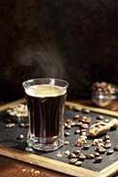 Steaming black coffee with coffee beans