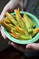 A woman holding a green antique dish with zucchini