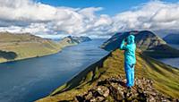 Young woman looks over the fjord landscape, the mo